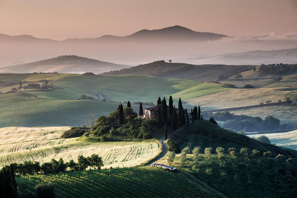 Val d'Orcia, Tuscany, Italy. A lonely farmhouse with cypress and olive trees, rolling hills.