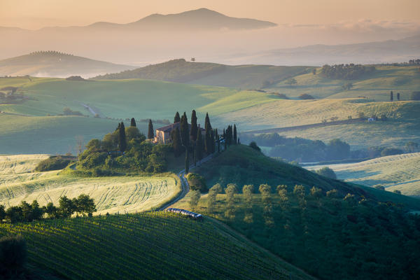 Val d'Orcia, Tuscany, Italy. A lonely farmhouse with cypress and olive trees, rolling hills.