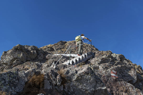 Italy, Trentino Alto Adige, Non valley, woman hiker climbs to the summit of Luco Mount on the steep wooden stairs.