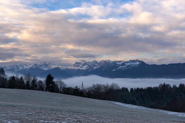 Italy, Trentino Alto Adige, Non valley, Dawn on Maddale group and fog over the Seio village in a winter day.