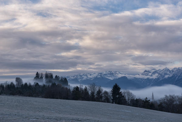 Italy, Trentino Alto Adige, Non valley, Dawn on Maddale group and fog over the Seio village in a winter day.
