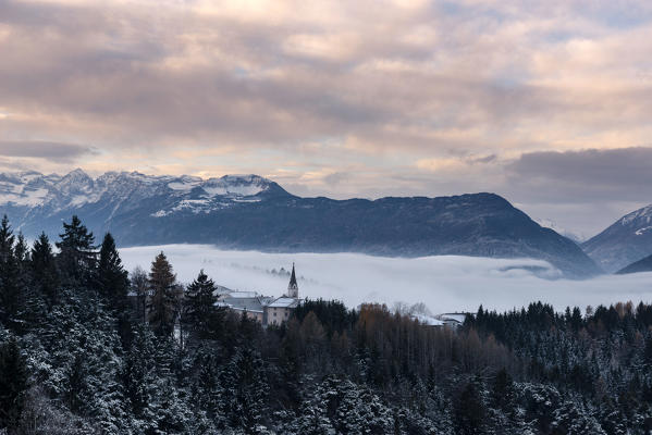 Italy, Trentino Alto Adige, Non valley, Dawn on Maddale group and fog over the Seio village in a winter day.