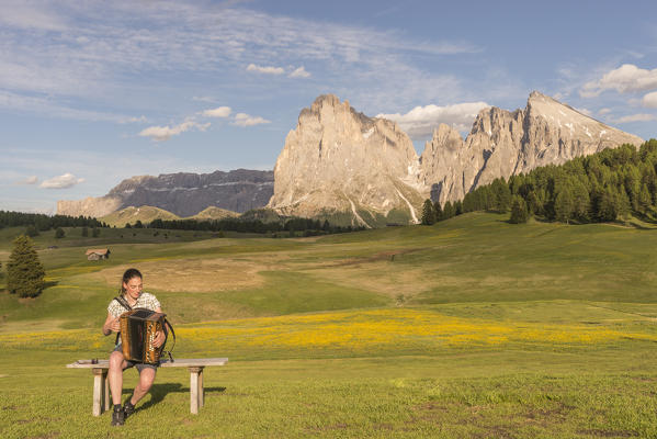 Alpe di Siusi/Seiser Alm, Dolomites, South Tyrol, Italy. Young woman playing with the accordion at the Alpe di Siusi