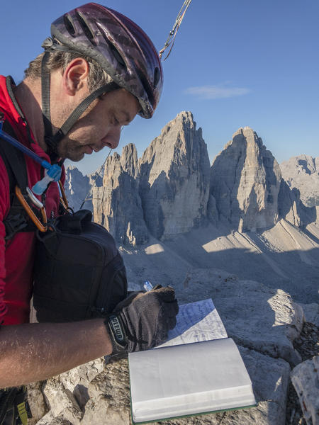 Sesto/Sexten, Dolomites, South Tyrol, province of Bolzano, Italy. Hiker sign the book of the summit of Monte Paterno/Paternkofel on the Tre Cime di Lavaredo/Drei Zinnen 