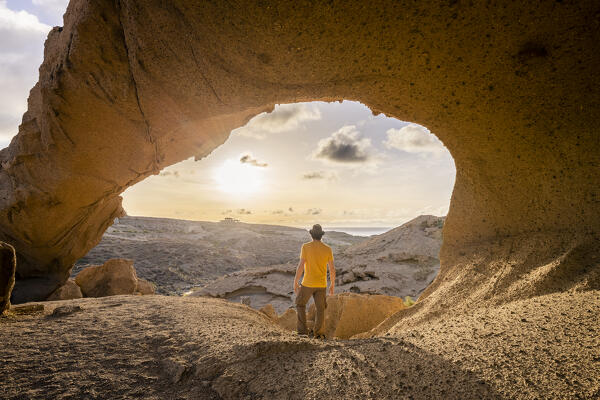 Spain,Canary Islands,Tenerife,Santa Cruz de Tenerife, a man standing under the natural formation of volcanic tuff of the Arco de Tajao (MR)