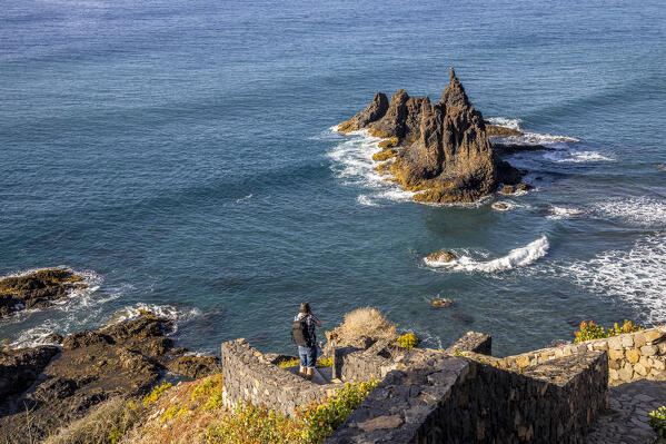 Spain,Canary Islands,Tenerife,Anaga Rural Park, a man photographing Roque de la Rapadura at Playa de Benijo (MR)