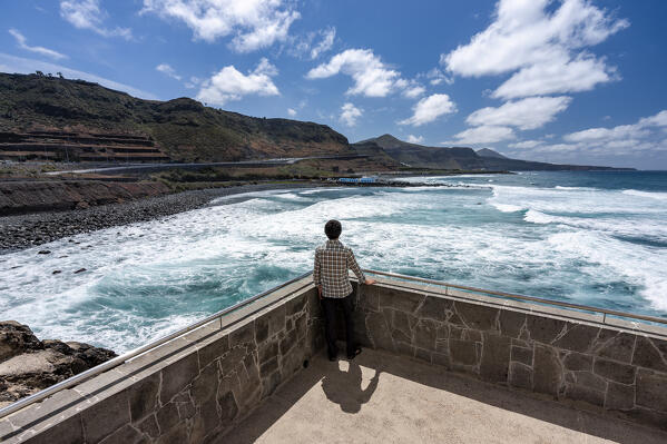 Spain, Canary Islands, Gran Canaria,El Roque, a man admires the waves from a terrace overlooking the sea (MR)