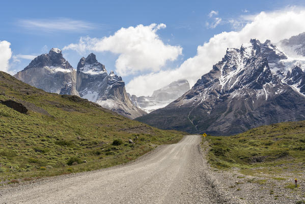 Dirt road with Paine Horns and Cerro Paine in summer. Torres del Paine National Park, Ultima Esperanza province, Magallanes region, Chile.