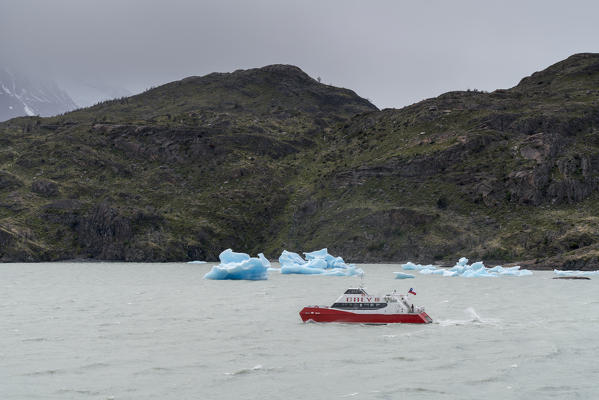 Ferry on Grey Lake with icebergs on a rainy day in summer. Torres del Paine National Park, Ultima Esperanza province, Magallanes region, Chile.