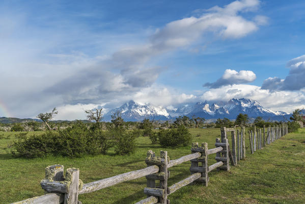 Fence with Paine Horns, Cerro Paine and Cerro Paine Grande in the background in summer. Torres del Paine National Park, Ultima Esperanza province, Magallanes region, Chile.