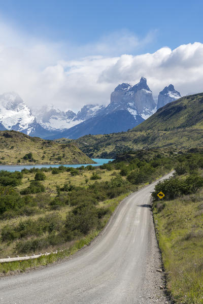 Dirt road and Lake Pehoé and Paine Horns in the background, in summer. Torres del Paine National Park, Ultima Esperanza province, Magallanes region, Chile.