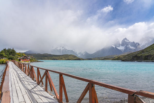 Boardwalk to Hosteria Pehoé in summer, with Paine Horns in the background. Torres del Paine National Park, Ultima Esperanza province, Magallanes region, Chile.