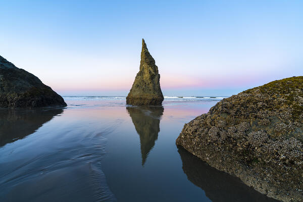The Wizard's hat sea stack reflecting on low tide on Bandon Beach at dawn. Bandon, Coos county, Oregon, USA.