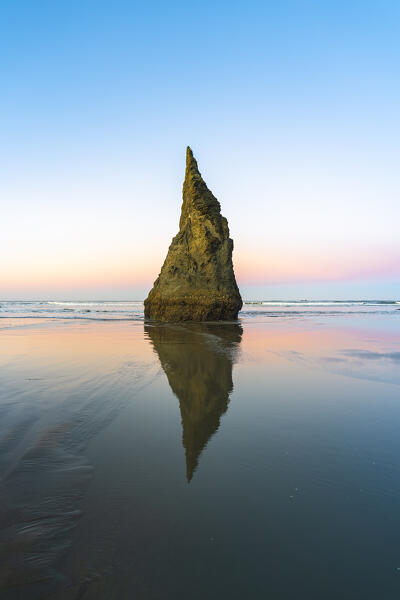 The Wizard's hat sea stack reflecting on low tide on Bandon Beach at dawn. Bandon, Coos county, Oregon, USA.