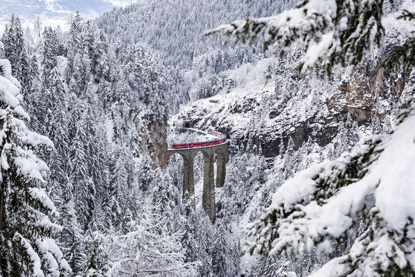 The Bernina Express red train as it passes over the Landwasser bridge, Filisur, Graubunden, Switzerland, Europe.