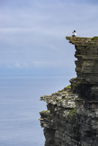 Woman on the edge of a cliff at Cliffs of Moher, Liscannor, Munster, Co.Clare, Ireland, Europe.