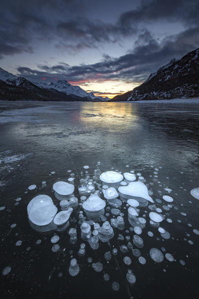 Frozen gas bubbles trapped in the ice after sunset. Silvaplana Lake, Silvaplana, Engadin, Graubunden, Switzerland, Europe.