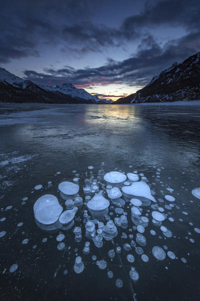 Frozen gas bubbles trapped in the ice after sunset. Silvaplana Lake, Silvaplana, Engadin, Graubunden, Switzerland, Europe.