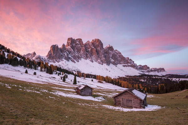 Sunrise with two wooden lodges and Odle Dolomites. Malga Gampen, Funes, Bolzano, Trentino Alto Adige - Sudtirol, Italy, Europe.