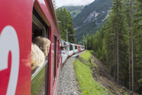 Tourists looking out of the red train wondows, Graubunden, Switzerland