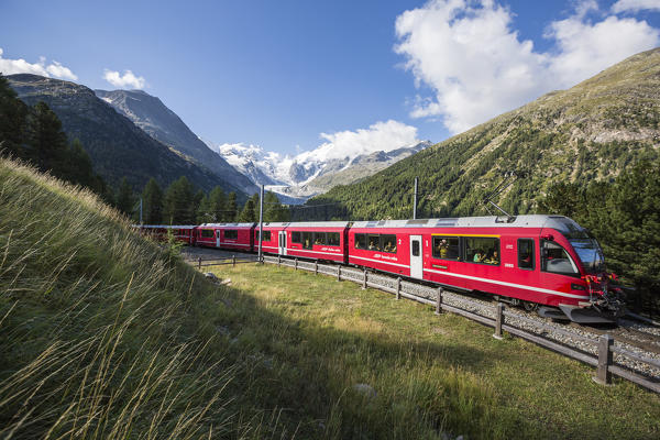 Bernina Red Train and Morteratsch glacier on the background. Engadin, Graubunden, Switzerland.