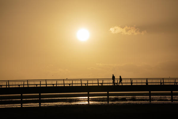 Backlight with people walking on the bridge. Mont-Saint-Michel, Normandy, France.