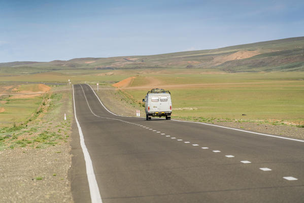 Soviet vehicle driving along a straight paved road. Bayandalai district, South Gobi province, Mongolia.