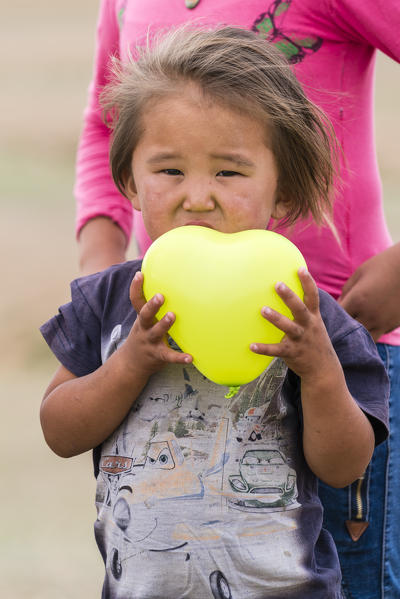 Portrait of a little boy with a yellow balloon in hands. South Gobi Province, Mongolia.