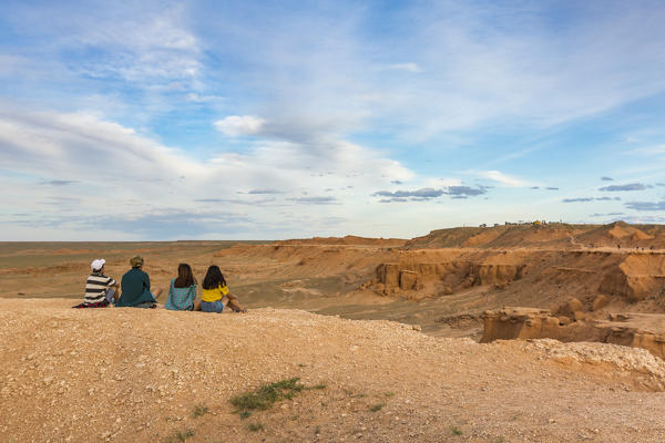Tourists sitting at Flaming cliffs, Bajanzag, South Gobi province, Mongolia.