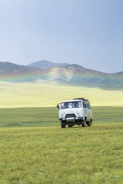 Rainbow and Soviet vehicle driving in the Mongolian steppe. Ovorkhangai province, Mongolia.