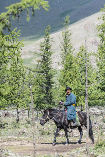 Mongolian man riding a horse in White Lake National Park. Tariat district, North Hangay province, Mongolia.