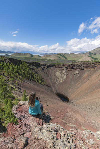 Woman sitting over Khorgo volcano crater and White Lake in the background. Tariat district, North Hangay province, Mongolia.
