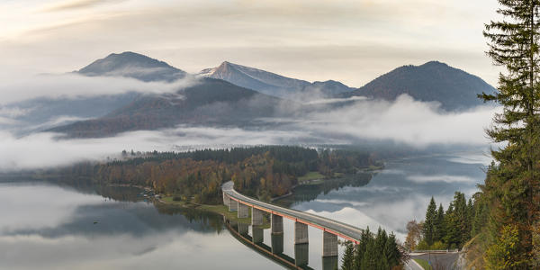 Sylvenstein Lake and bridge surrounded by the morning mist. Bad Tölz-Wolfratshausen district, Bavaria, Germany.