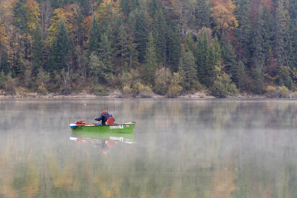Man fishing on Sylvenstein Lake in the morning. Bad Tölz-Wolfratshausen district, Bavaria, Germany.