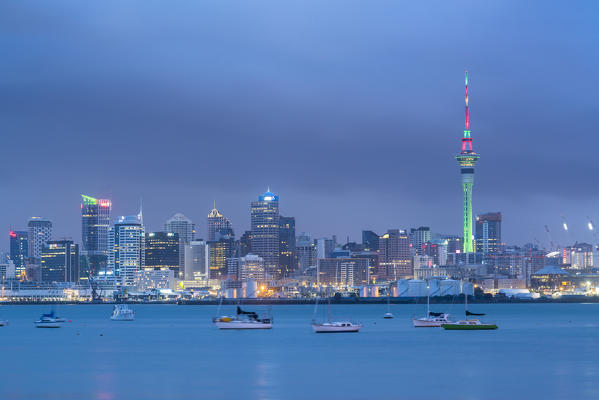 Skyline of Auckland CBD under a gloomy sky at dusk. Auckland City, Auckland region, North Island, New Zealand.