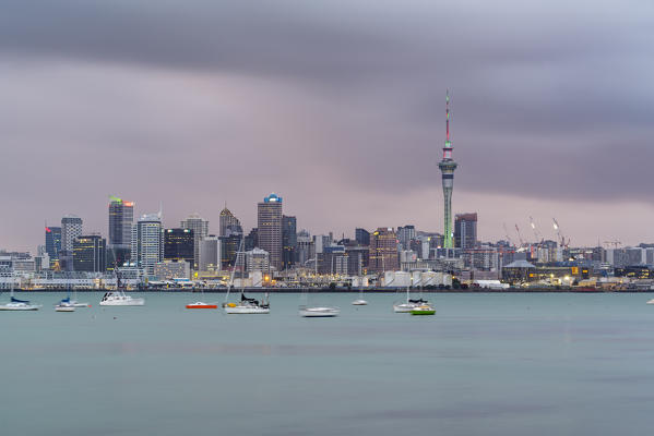 Skyline of Auckland CBD under a gloomy sky at dusk. Auckland City, Auckland region, North Island, New Zealand.