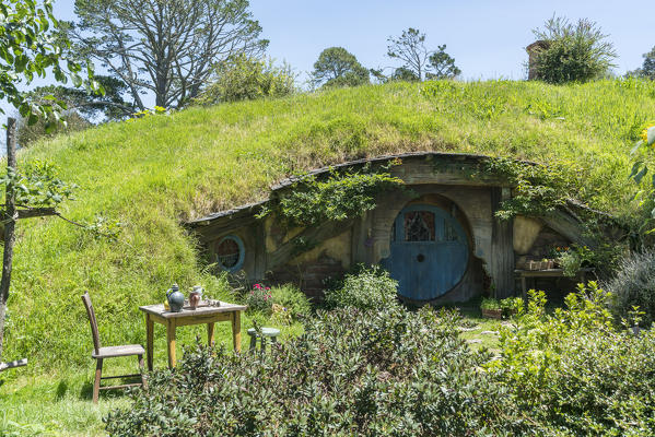 Hobbit house with table and chair in the garden. Hobbiton Movie Set, Matamata, Waikato region, North Island, New Zealand.