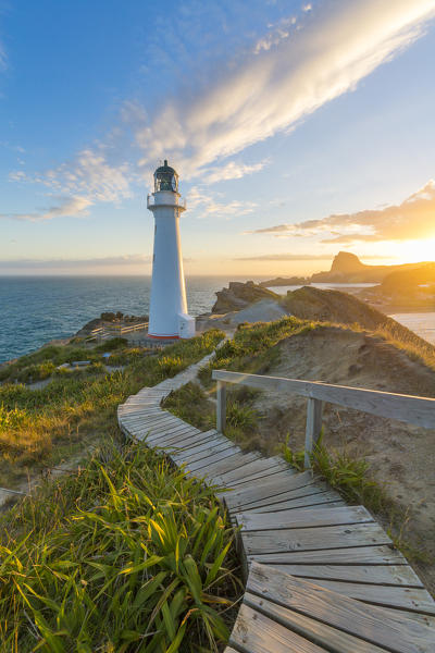 The sun is setting down behind Castle Rock and Castlepoint lighthouse.  Castlepoint, Wairarapa region, North Island, New Zealand.