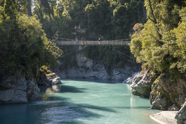 People standing on a boardwalk over Hokitika river. Hokitika, West Coast region, South Island, New Zealand.