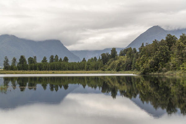 Lake Matheson reflections under a moody sky. Fox Glacier Village, West Coast region, South Island, New Zealand.