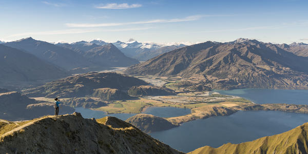 Woman taking photographs of Lake Wanaka and Mt Aspiring NP from Roys Peak track. Wanaka, Queenstown Lakes district, Otago region, South Island, New Zealand.