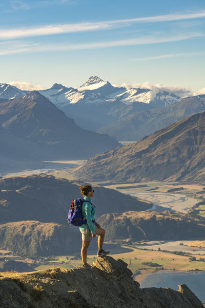 Woman admiring Lake Wanaka and Mount Aspiring NP from Roys Peak. Wanaka, Queenstown Lakes district, Otago region, South Island, New Zealand. (MR)