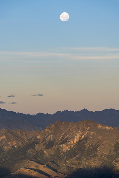 Moon over Mt Aspiring NP from Roys Peak lookout at sunset. Wanaka, Queenstown Lakes district, Otago region, South Island, New Zealand.