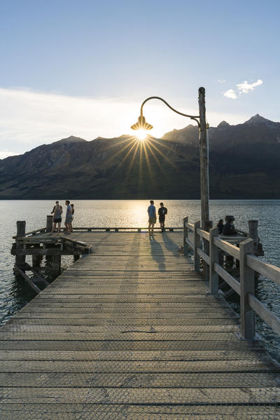 People on the jetty on Lake Wakatipu just before sunset. Glenorchy, Queenstown Lakes district, Otago region, South Island, New Zealand.