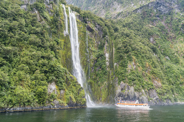 Touristic boat facing Stirling Falls in Milford Sound. Fiordland NP, Southland district, Southland region, South Island, New Zealand.
