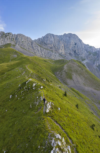 Aerial view of a man walking at Passo degli Agnelli in front of Pizzo della Presolana at dawn. Castione della Presolana, Bergamo province, upper Val Seriana, Lombardy, Italy.