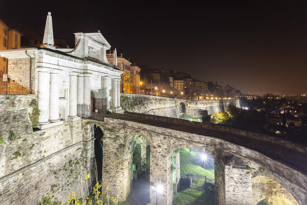 View of the stone bridge leading into one of the old doors of Bergamo city, Porta San Giacomo, in Upper Town (Città Alta) at night. Bergamo, Lombardy, Italy.
