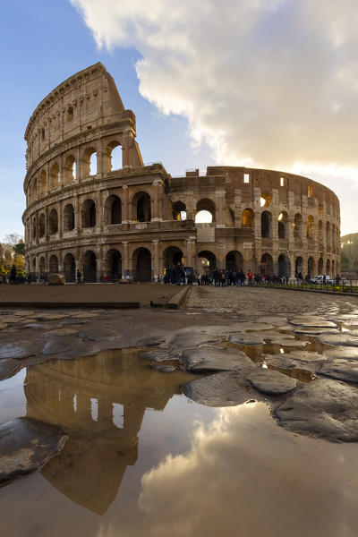 View of the Colosseum reflecting on a puddle during a winter sunrise. Rome, Lazio, Italy. 