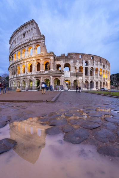 View of the Colosseum reflecting on a puddle during a winter evening. Rome, Lazio, Italy. 