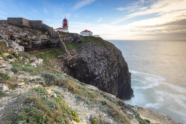 The cliffs and lighthouse of Cabo De San Vicente at sunset, overlooking the Atlantic Ocean. Sagres, Vila do Bispo, Algarve, Portugal, Europe.